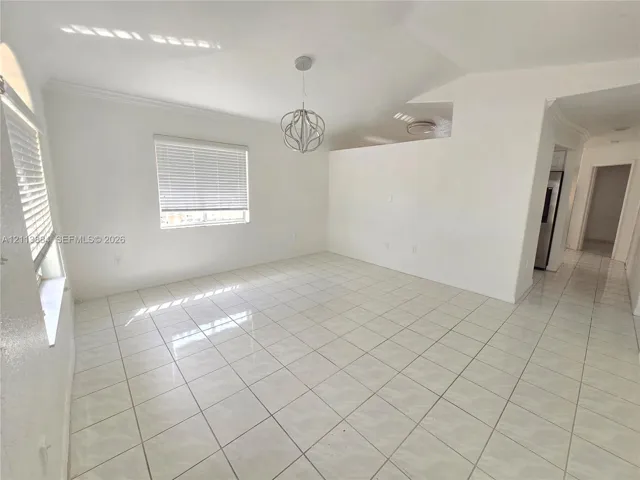 Open-concept room featuring light tile flooring, high vaulted ceilings, architectural archway accents, and a contemporary spherical pendant light fixture