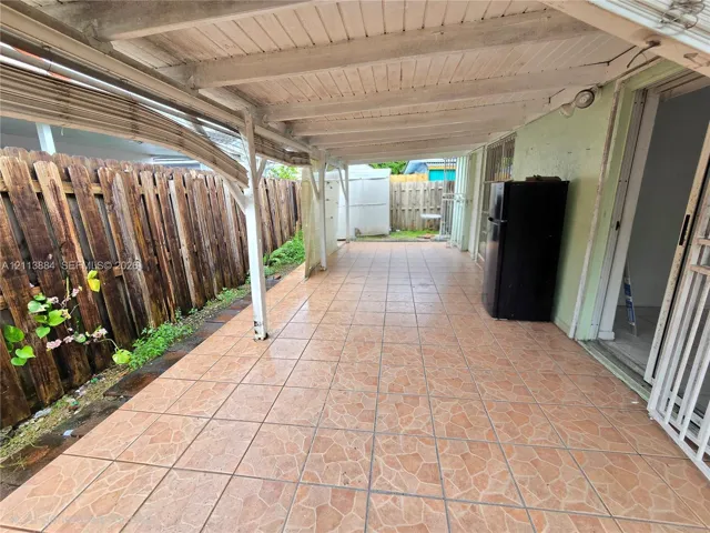 Covered outdoor patio featuring tile flooring, a painted wooden ceiling, and vertical wood-plank perimeter fencing