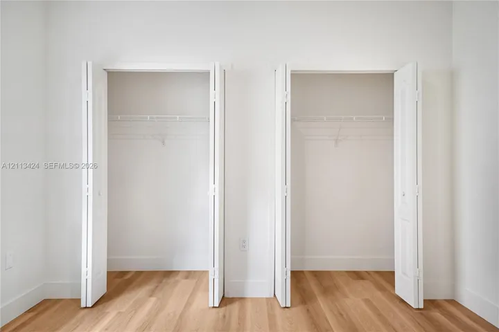 Dual closets featuring white bi-fold doors and integrated wire shelving, complemented by wood-finish flooring
