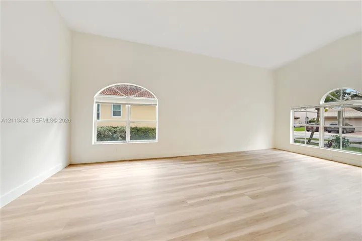 Spacious interior featuring vaulted ceilings, neutral wall tones, wood-finish flooring, and arched windows