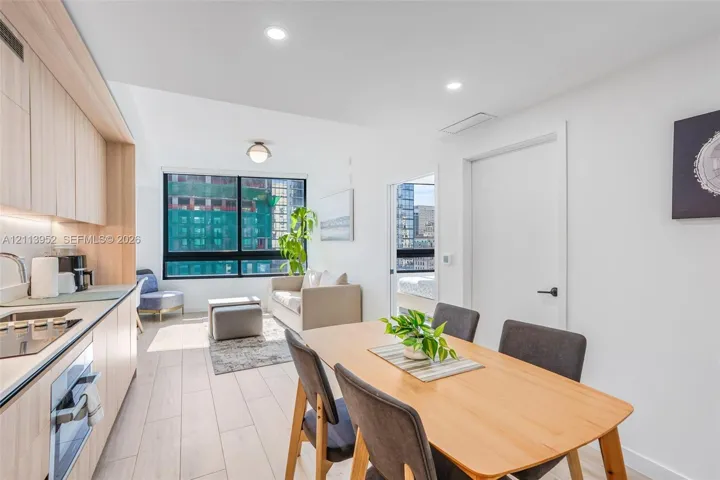 Contemporary kitchen featuring light-toned cabinetry, built-in electric cooktop, and flush-mount integrated lighting