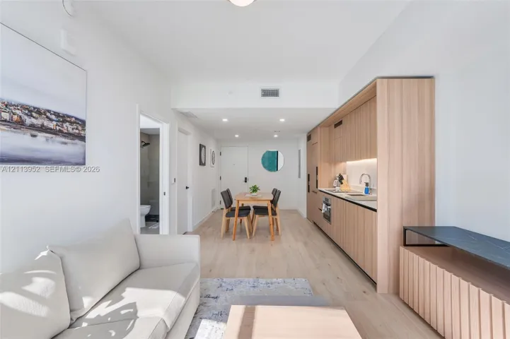 Kitchen featuring light wood-finish cabinetry, recessed lighting, integrated appliances, and light-toned wood-finish flooring