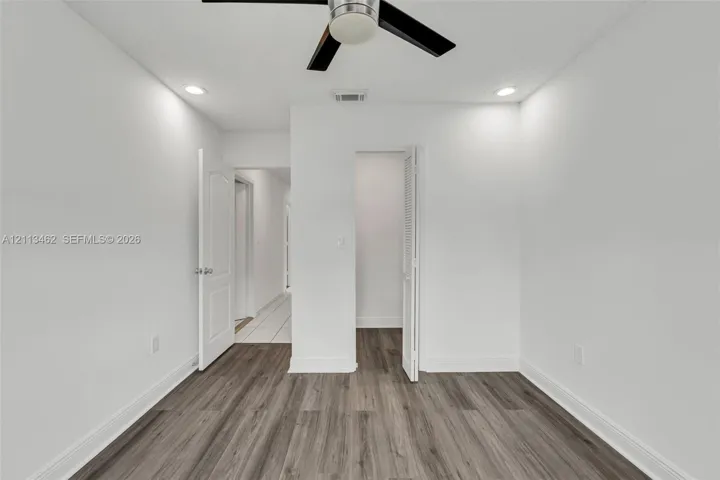 Wood-finish flooring, recessed lighting, ceiling fan with light fixture, louvered-door closet, and raised-panel interior door