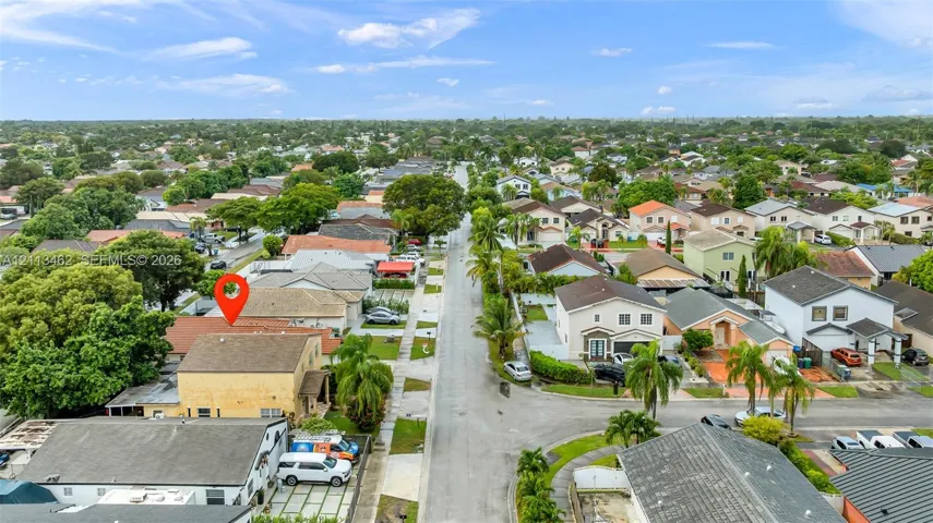 Aerial perspective of the residential property featuring a pitched roof, exterior stucco siding, and a paved driveway