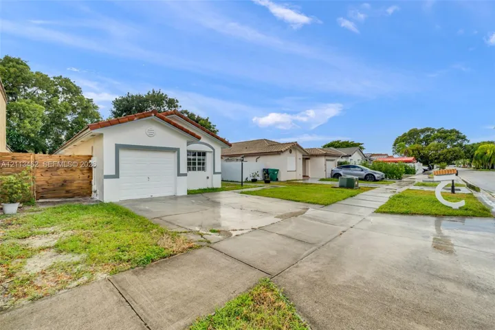 Single-story residence featuring a tile roof, an attached garage, and a wood-panel fence