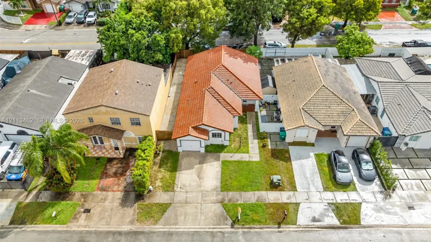Single-story residence featuring a terracotta-tiled roof, white exterior finish, integrated one-car garage, and a concrete driveway
