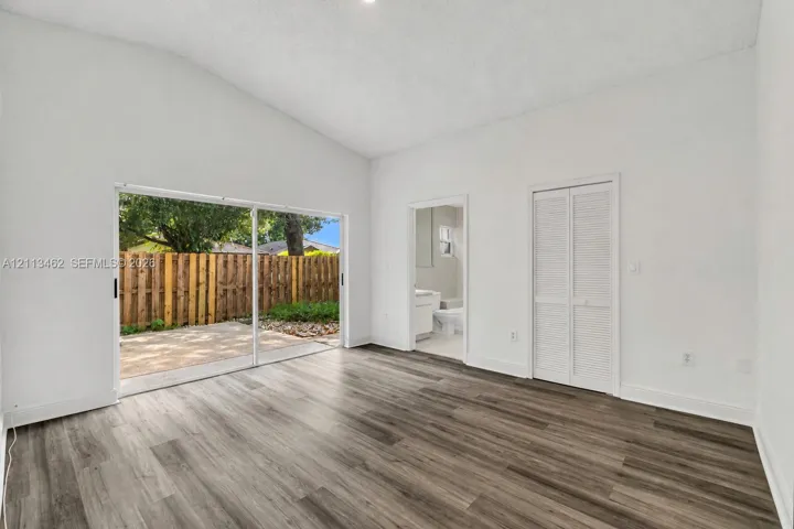 Vaulted ceiling, wood-finish flooring, sliding glass door, and louvered closet doors