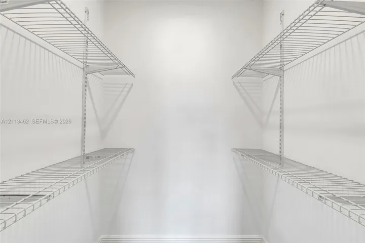 Storage space featuring dual-level white wire shelving units mounted on vertical wall tracks