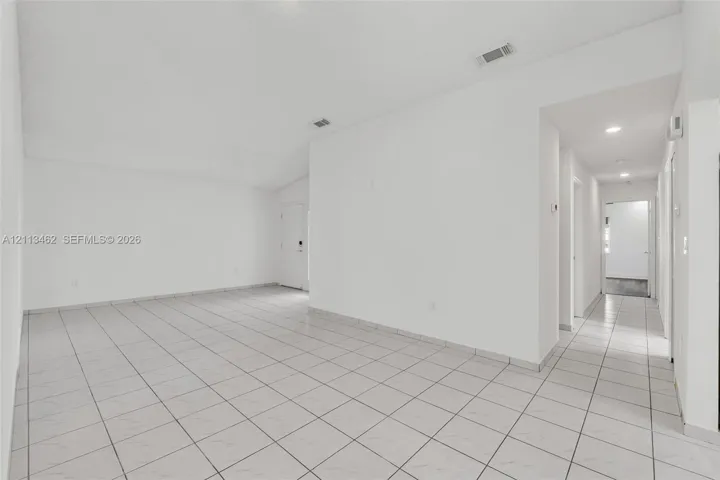 Open interior area featuring vaulted ceilings, neutral wall finishes, and light-toned tile flooring throughout