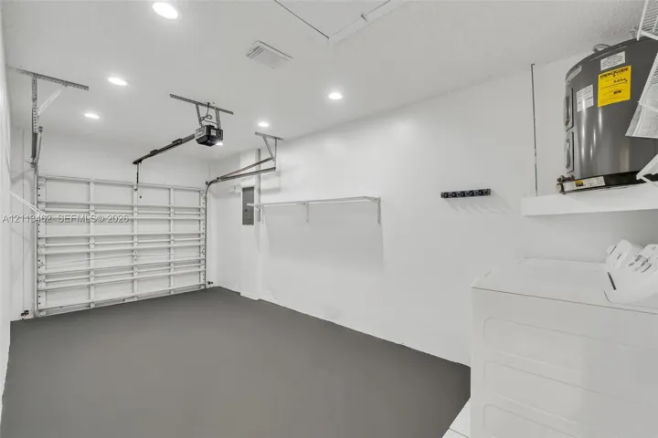 Finished garage featuring grey epoxy-coated flooring, recessed ceiling lighting, a metal garage door, and built-in wall-mounted shelving