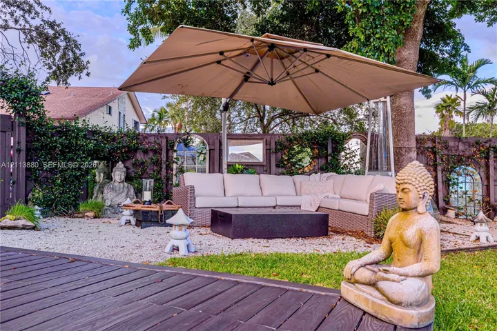 Outdoor living area featuring a wooden deck, crushed stone ground cover, and a dark-toned privacy fence with inset decorative mirrors