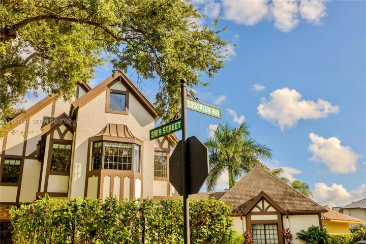 Tudor-style exterior featuring stucco facade with timber framing, multi-pane bay windows, and mature landscaping