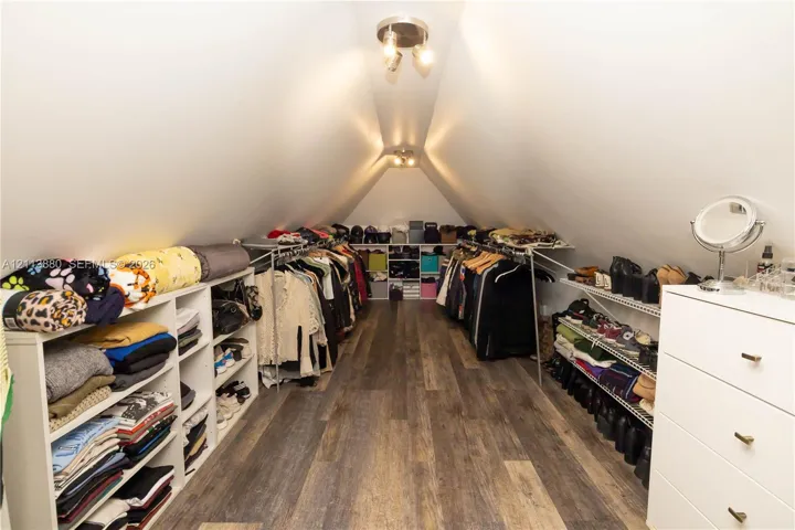 Finished attic space featuring vaulted ceilings, wood-finish flooring, and multi-light flush mount ceiling fixtures