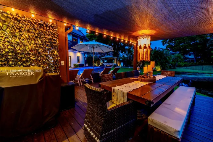 Covered outdoor deck featuring wood-finish decking, integrated string lighting, and a privacy screen with decorative faux foliage