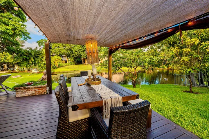 Outdoor deck featuring wood-finish decking, a fabric sun shade, brick planter, and waterfront exposure