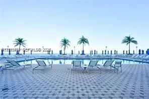 Swimming pool with a tile-patterned deck and perimeter palm trees