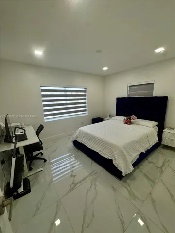 Large-format tile flooring with vein detailing, recessed ceiling lighting, and windows featuring integrated dual-layered roller shades