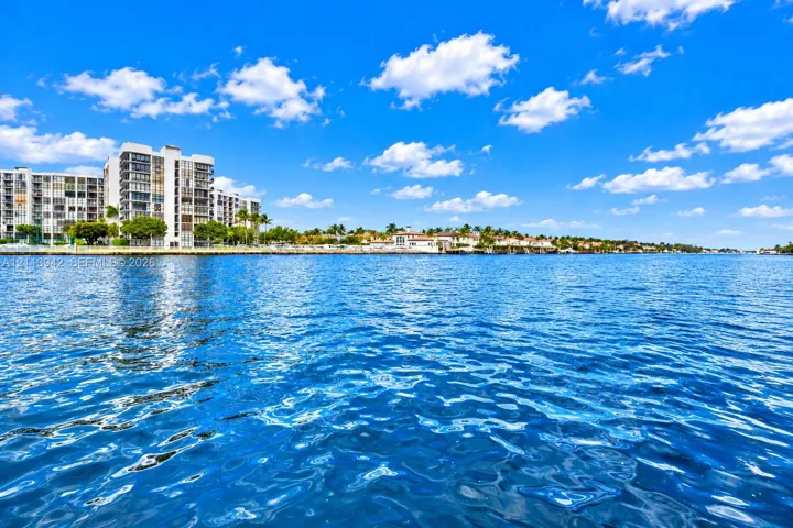 Direct waterfront setting featuring expansive water frontage, multi-story coastal architecture, and mature palm tree landscaping
