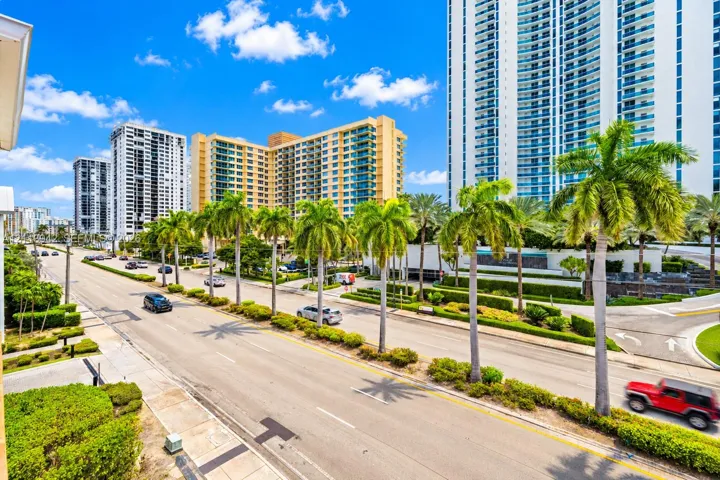High-rise urban streetscape featuring palm-lined boulevards, meticulously manicured landscaping, and contemporary multi-story residential architecture