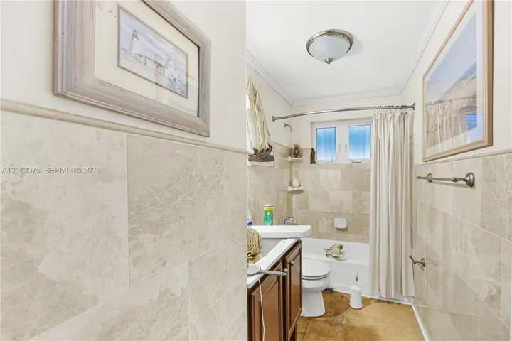 Full-height stone wall tiling with matching crown molding, wood-finish cabinetry, and built-in recessed wall shelving