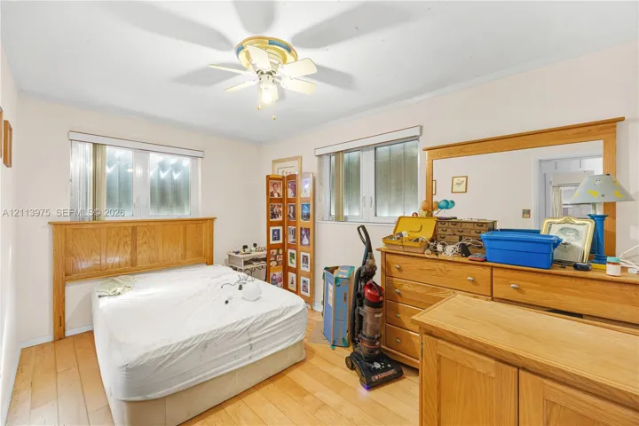 Wood-finish flooring, dual windows with blinds, and a central ceiling fan with integrated light fixture