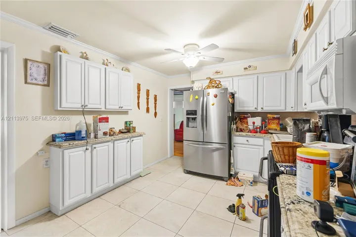 Kitchen featuring white cabinetry, stone-finish countertops, tile flooring, stainless steel French door refrigerator, and built-in microwave