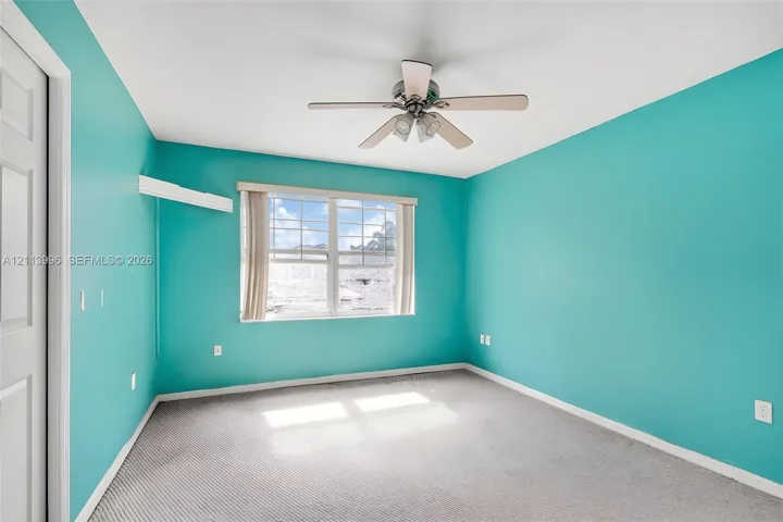 Room featuring carpeted flooring, a multi-blade ceiling fan with integrated lighting, and a multi-pane window