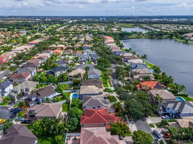 Aerial perspective featuring residential lots, paved street infrastructure, and proximity to a large water basin