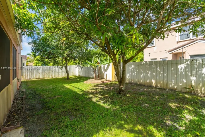 Backyard featuring privacy fencing, mature trees, and ground-level plantings