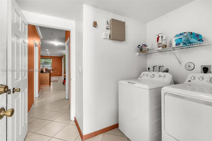 Laundry area featuring ceramic tile flooring, dedicated washer and dryer hookups, and a built-in wire shelving unit