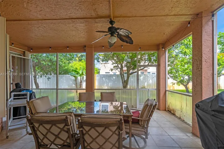 Screened-in covered patio featuring tile flooring, a ceiling fan, and string lighting