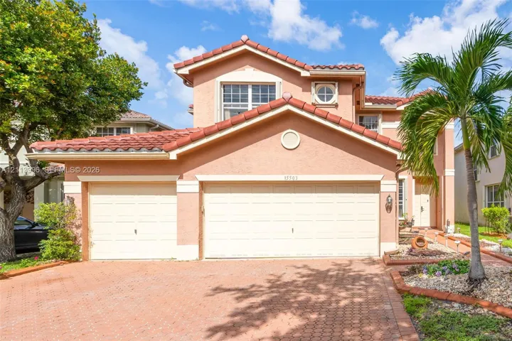Two-story residence featuring a textured stucco exterior, red tile roof, multi-car garage, and a brick-paved driveway