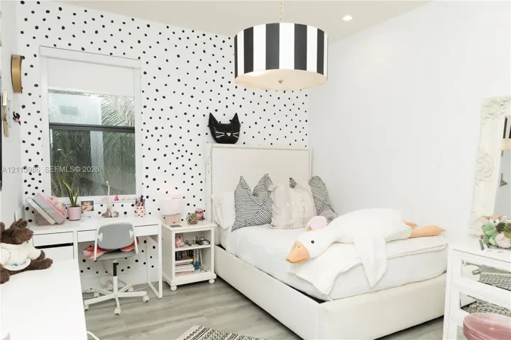 Polka-dot patterned accent wall, grey wood-finish flooring, and recessed ceiling lighting