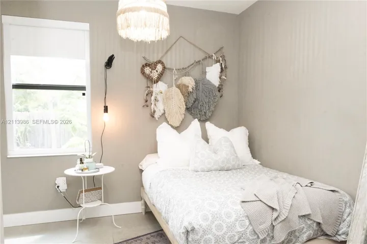 Ground floor bedroom, Neutral-toned interior space featuring a single-hung window, a decorative pendant light fixture, and a wall-mounted light fixture with a corded finish