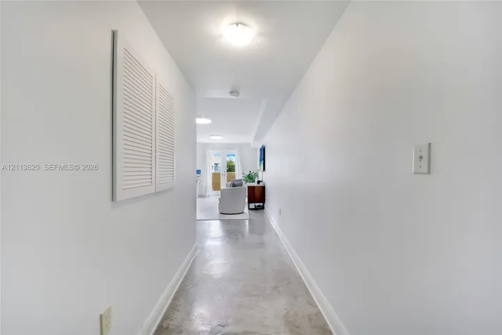 Hallway featuring polished concrete flooring, white walls, louvered closet doors, and flush-mount ceiling lighting