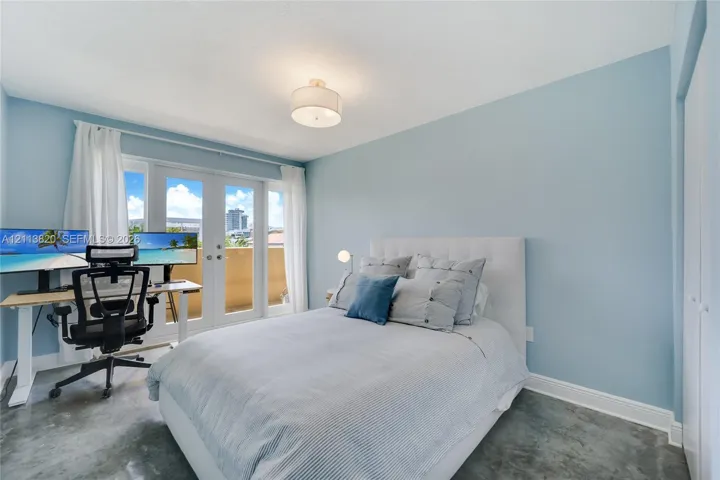 Polished concrete flooring, dual-pane French doors with exterior access, drum-style ceiling light fixture, and white double-door closet cabinetry