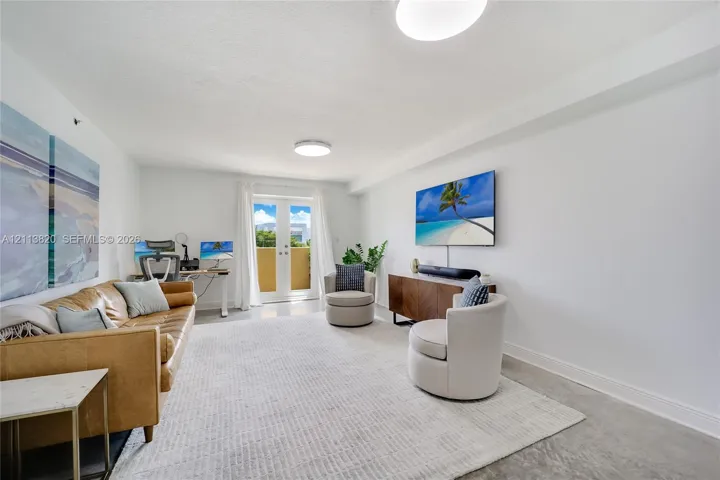 Neutral-toned interior space featuring polished concrete flooring, white walls, and French doors providing access to an exterior balcony