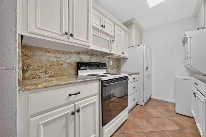 Galley-style kitchen featuring wood cabinetry & granite countertops