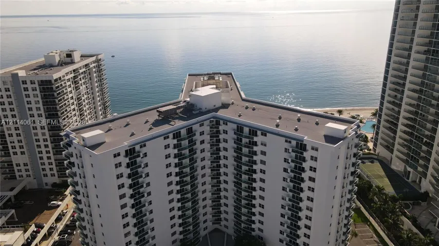 High-rise residential building featuring white exterior cladding, a multi-wing structural design, and private balconies with glass railings