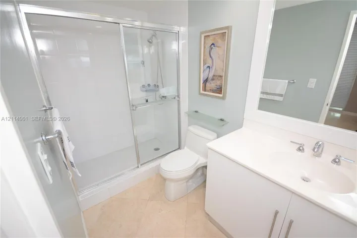 Bathroom featuring a glass-enclosed shower with tiled walls, a white vanity with an integrated basin, a polished-chrome faucet, and tile flooring