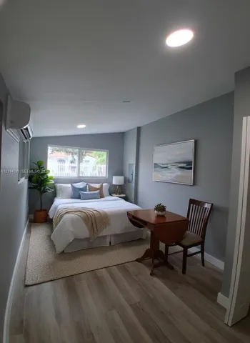 Wood-finish flooring, recessed lighting, wall-mounted climate control unit, and a horizontal sliding window