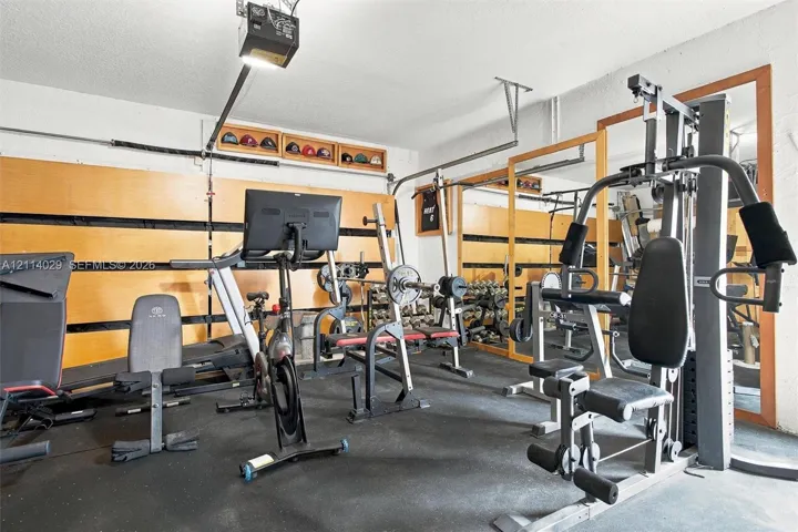 Garage space featuring wall-mounted slatwall storage systems, full-length wall mirrors, and durable floor surfacing