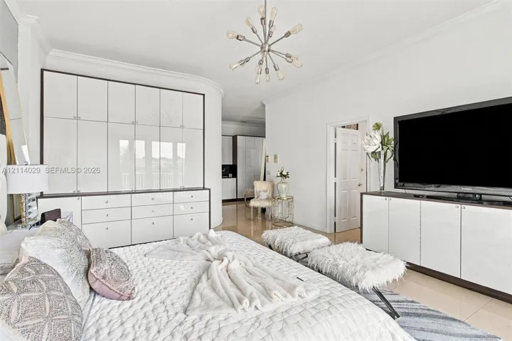 Floor-to-ceiling built-in white cabinetry, polished stone flooring, custom integrated media console, and a contemporary multi-arm sputnik chandelier