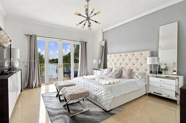 Polished tile flooring, crown molding, multi-light modern chandelier, and double glass-paned doors opening to a private balcony