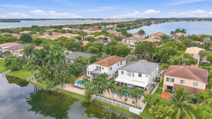 Waterfront property featuring private in-ground swimming pools, paved pool decks, and white perimeter fencing