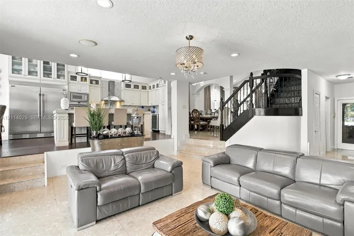 Kitchen featuring white cabinetry, stainless steel appliances, and a central island with bar seating, highlighted by recessed lighting and a decorative chandelier