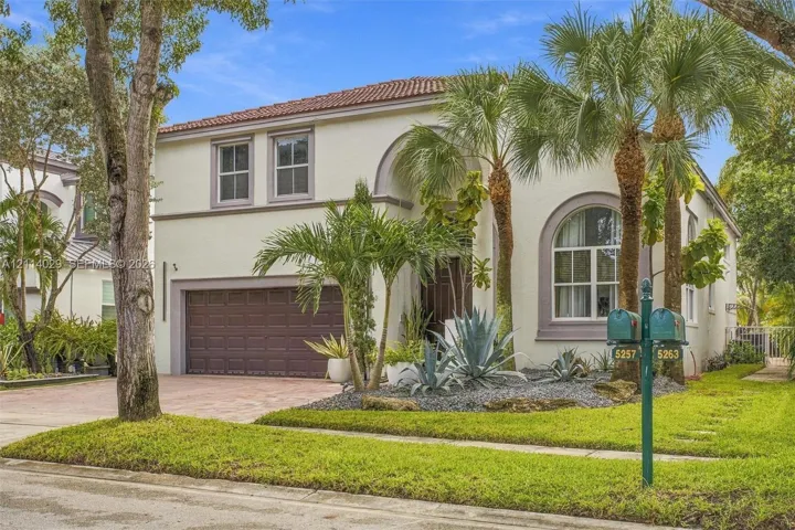 Stucco exterior featuring arched windows, a barrel tile roof, and an attached two-car garage