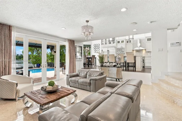 Open-concept floor plan featuring polished stone flooring, recessed lighting, white cabinetry, and multi-panel glass doors with exterior patio and pool access