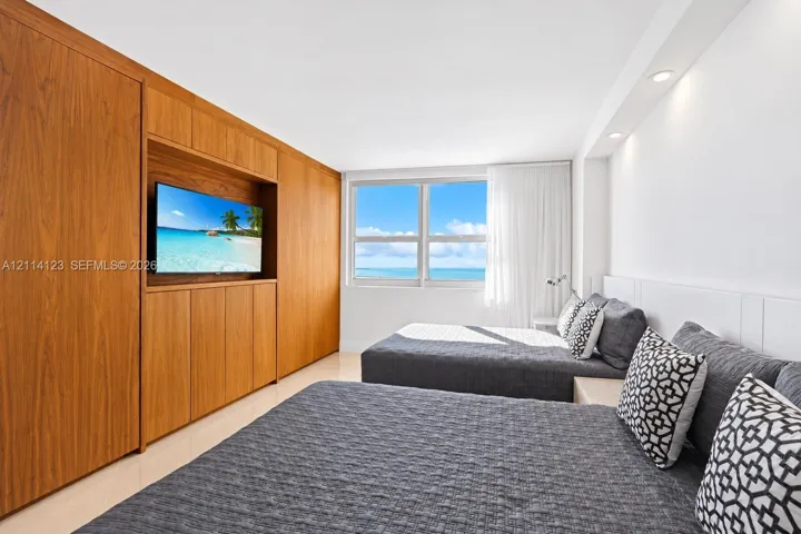 Custom wood-veneer cabinetry with integrated media shelving, large windows with water scenery, and recessed lighting