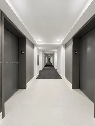 Hallway featuring large-format tile flooring, textured charcoal wall coverings, matte charcoal door frames, and recessed ceiling lighting